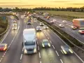 Traffico intenso su un'autostrada al tramonto. Auto e camion sfrecciano, creando scie luminose. Chissà se il limite velocità autostrada 150 dove è rispettato.