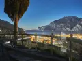 Peschiera del Garda di sera: un panorama mozzafiato con luci scintillanti, montagne imponenti e un cielo stellato. Ideale per una serata romantica.