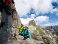 Escursionisti in cordata si godono un giro del Catinaccio, con cime rocciose e cielo azzurro.