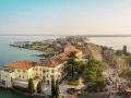 Vista aerea del centro storico di Sirmione, con edifici storici, lago e passeggiata affollata.