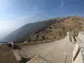 Strada tortuosa sul Monte Palon, Grappa, con vista panoramica sulle montagne e cielo azzurro.