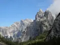 Imponenti cime rocciose dei monti di Framont si stagliano contro un cielo azzurro, con foreste di conifere ai loro piedi.