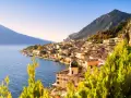 Un perfetto weekend sul lago di Garda: borgo colorato affacciato sull'acqua blu, montagne verdi e cielo limpido.