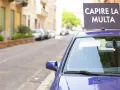 Auto blu parcheggiata in strada con cartello "Capire la multa". Divieto di sosta marciapiede ignorato.