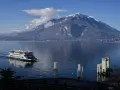 Traghetto sul lago di Como, con montagne innevate sullo sfondo e il pittoresco varenna centro storico.