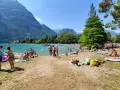 Spiaggia sabbioni Riva del Garda affollata di bagnanti sotto le montagne.
