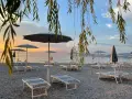 Alba sul lago di Garda, con lettini e ombrelloni pronti per accogliere i bagnanti sulle sue spiagge di sabbia.