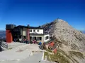 Rifugio Fraccaroli, un punto di ristoro in montagna. Per capire come arrivare, guarda la foto: un edificio con persone sedute all'esterno, con una vetta rocciosa sullo sfondo.