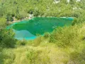 Lago di origine carsica a Forgaria nel Friuli, con acque cristalline di un verde smeraldo intenso, circondato da vegetazione lussureggiante.