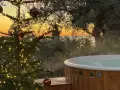 Un albero di Natale illuminato e una vasca idromassaggio fumante al tramonto sul Lago di Garda. Il camping è aperto tutto l'anno, un'oasi di relax invernale.