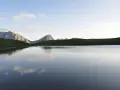 Sestriere estate: un lago alpino riflette le montagne e il cielo azzurro, un'oasi di pace.