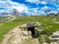 Un sentiero conduce a un rifugio di guerra sul Monte Piana, con le maestose Tre Cime di Lavaredo sullo sfondo.