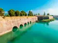 Fortificazioni storiche con archi in mattoni e acqua turchese, dove si trova Peschiera del Garda.