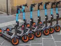 Monopattini elettrici Helbiz in fila, pronti per l'uso. La loro assicurazione è fondamentale per una mobilità sicura.