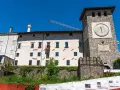 Torre dell'orologio e palazzi storici a Colloredo di Monte Albano, sotto un cielo azzurro.