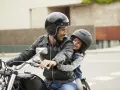 Padre e figlio sorridono in moto, rispettando il nuovo codice della strada per bambini in moto.