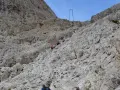 Escursionisti affrontano la **difficoltà** del sentiero verso il **Rifugio Re Alberto**, aggrappandosi a cavi d'acciaio su un ripido pendio roccioso.