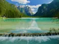 Splendido lago turchese incastonato tra montagne verdi, ideale per una toblacher see wanderung. Una cascata artificiale crea un effetto scenografico.