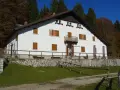 Il rifugio Città di Vittorio Veneto, immerso nel foliage autunnale, accoglie con la sua facciata bianca e le finestre con persiane in legno.