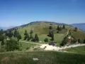 Panorami verdi e dolci colline del Pian delle Femene, con un rifugio e parcheggio.