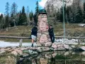 Coppia sorridente vicino a un monumento in pietra a Sappada, ideale per passeggiate facili.