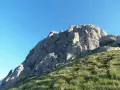 Vetta rocciosa con bandiera segnavento. Per col rodella come arrivare, segui il sentiero erboso verso la cima.