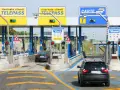 Casello autostradale con corsie Telepass e carte. Un'auto nera attende, forse per un mancato pagamento Telepass senza ricevuta.