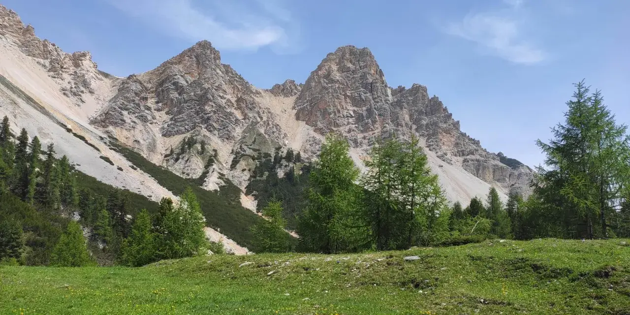 Prati verdi e larici svettano verso le imponenti cime rocciose, un paesaggio mozzafiato vicino alla malga Gran Fanes.