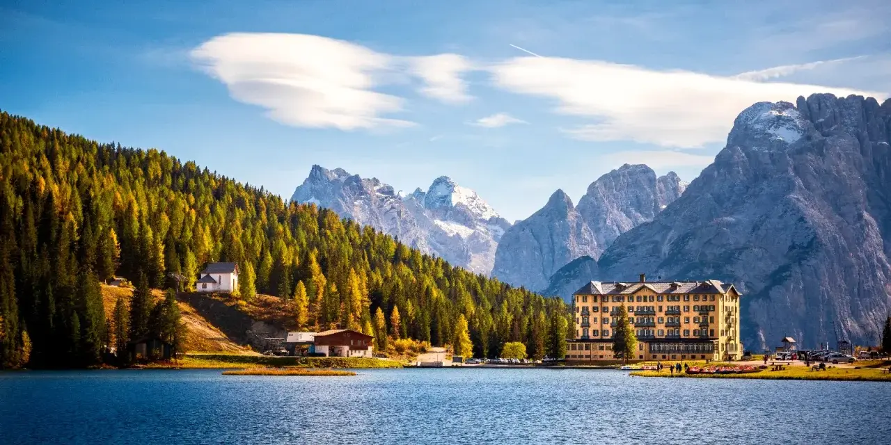 Paesaggio incantevole dei laghi del Veneto e Trentino, con un lago blu, montagne imponenti e un hotel storico.