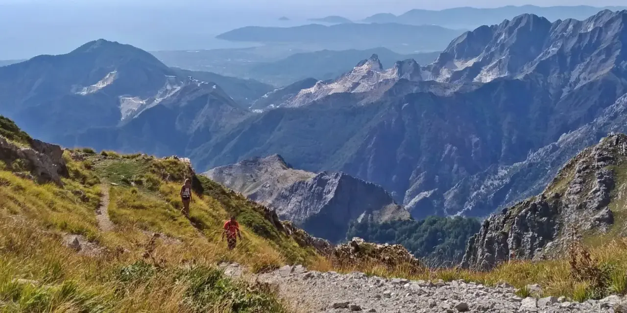 Due escursionisti affrontano la via Vandelli, un sentiero di montagna con notevole difficoltà, tra panorami mozzafiato e cave di marmo.