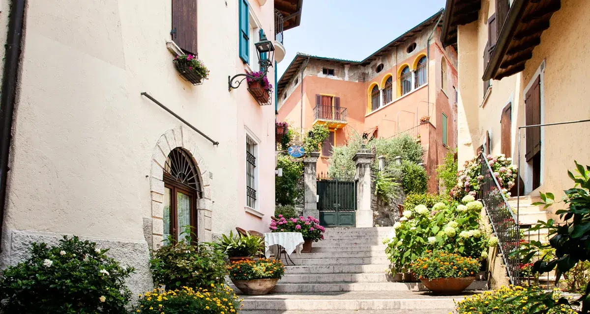 Un vicolo fiorito nel gardone riviera centro storico, con scale di pietra, case colorate e piante rigogliose.