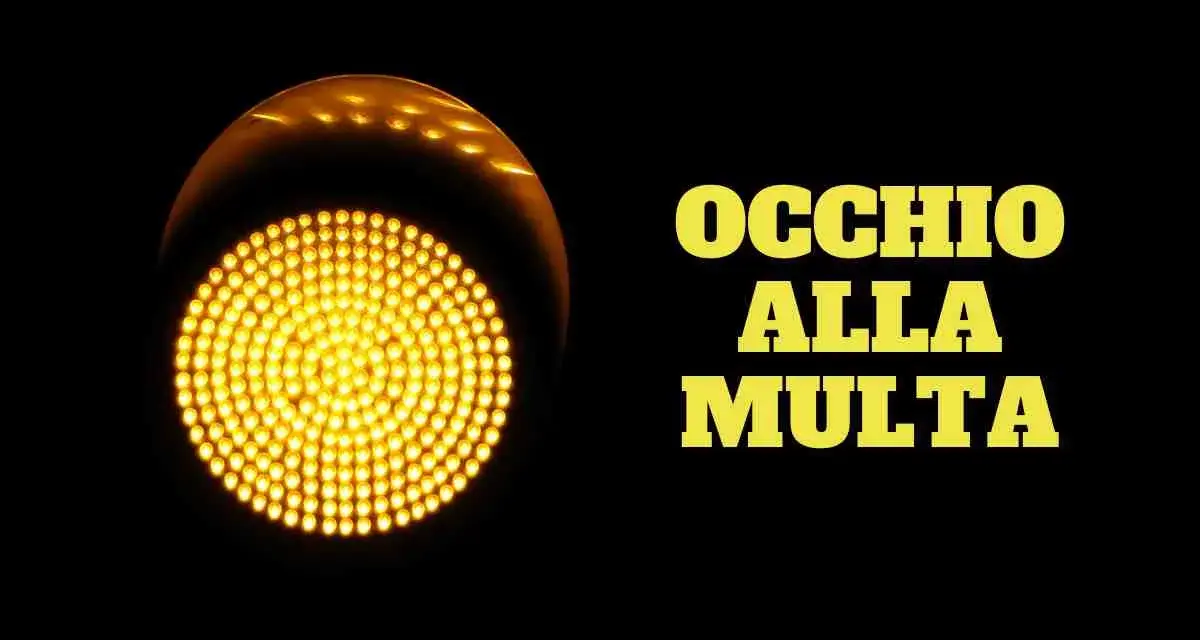 Semaforo giallo acceso, con la scritta "OCCHIO ALLA MULTA". Attenzione a non passare con il giallo, potresti ricevere una multa!