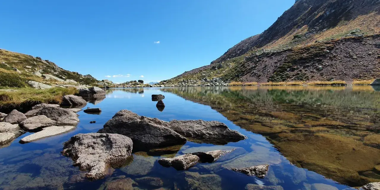Laghi alpini cristallini vicino Vipiteno, con rocce affioranti e riflessi del cielo azzurro e delle montagne.
