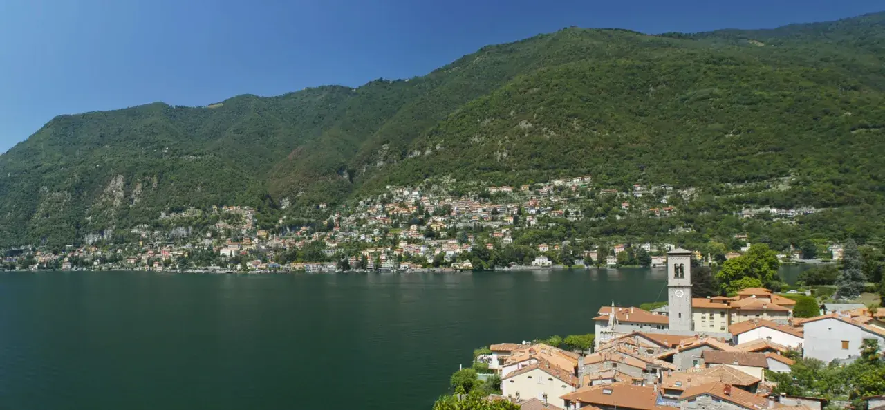 Un'ottima idea per sapere dove andare in montagna in Lombardia in giornata: un borgo pittoresco sul lago, con case colorate e montagne verdi sullo sfondo.