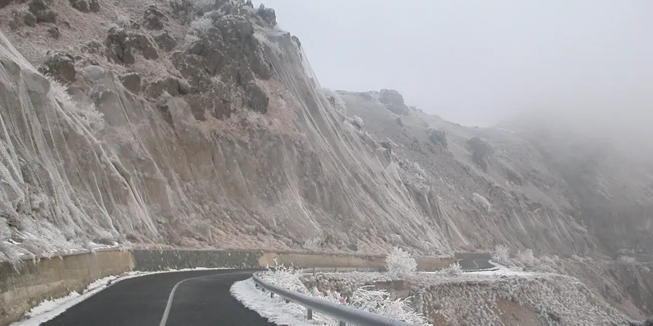 Strada innevata al passo del Faiallo, con rocce e vegetazione ghiacciate.