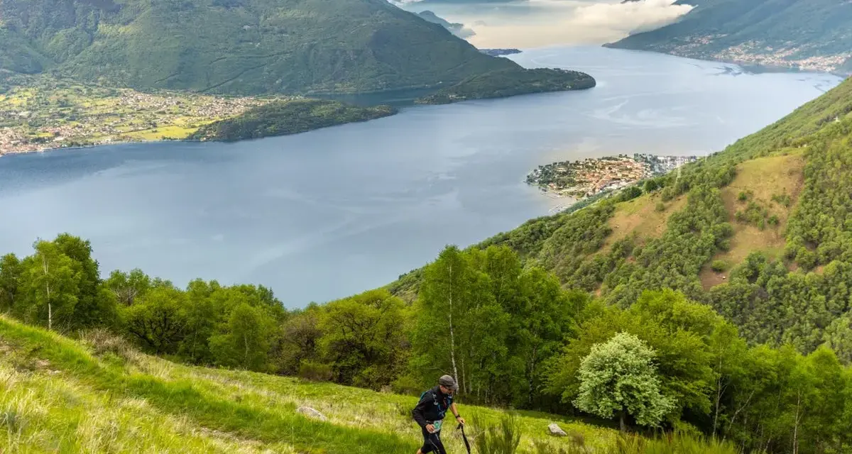 Un atleta corre su un sentiero erboso con vista sul Lago di Como, un'emozionante randonnée.