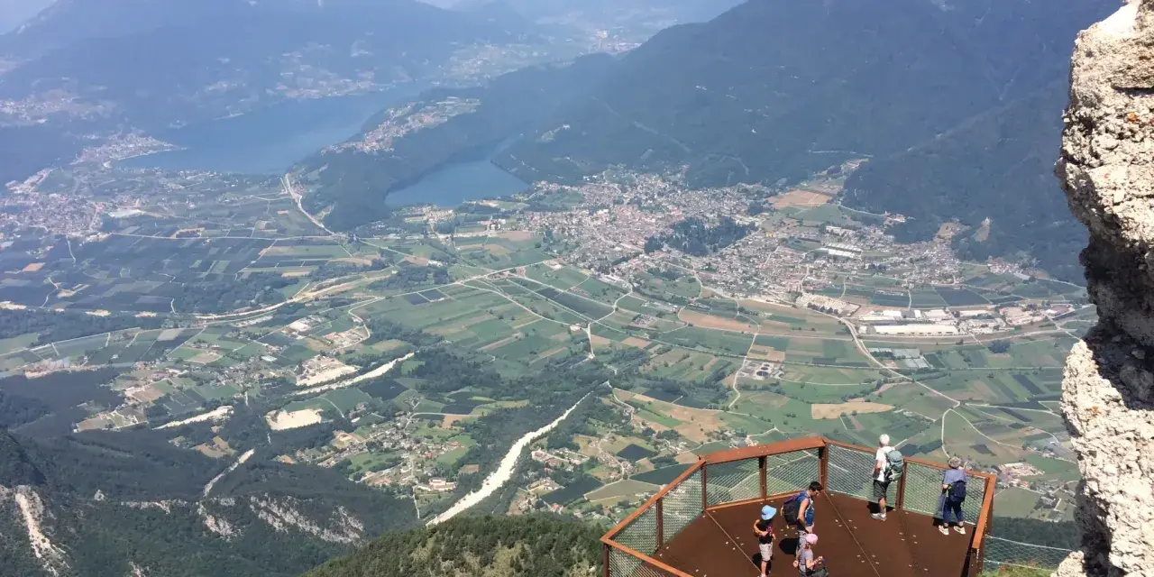 Vista panoramica dal Pizzo di Levico con un punto panoramico e persone che ammirano la valle sottostante.