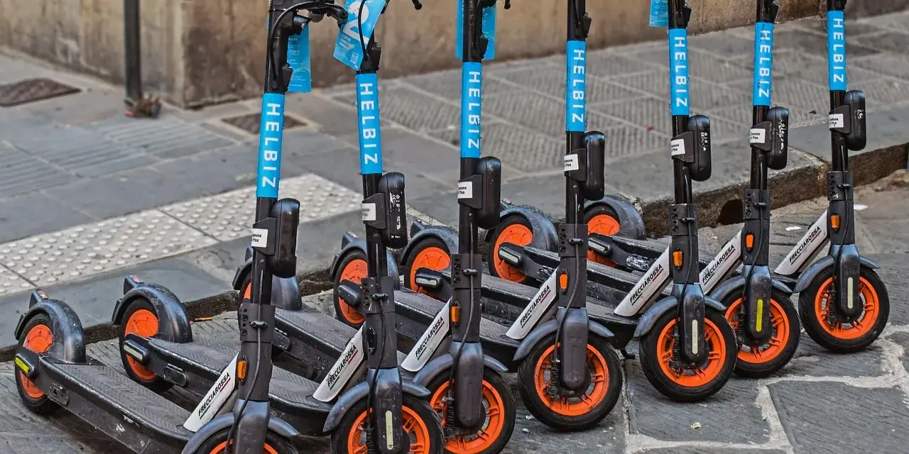 Monopattini elettrici Helbiz in fila, pronti per l'uso. La loro assicurazione è fondamentale per una mobilità sicura.