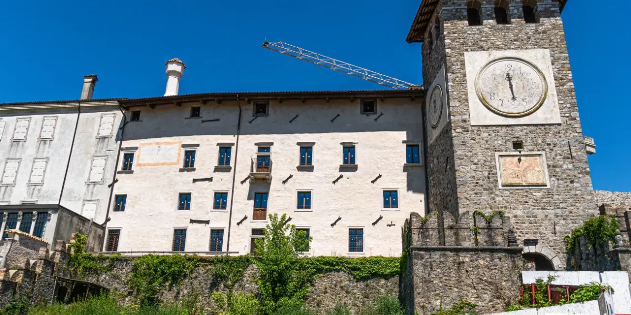 Torre dell'orologio e palazzi storici a Colloredo di Monte Albano, sotto un cielo azzurro.