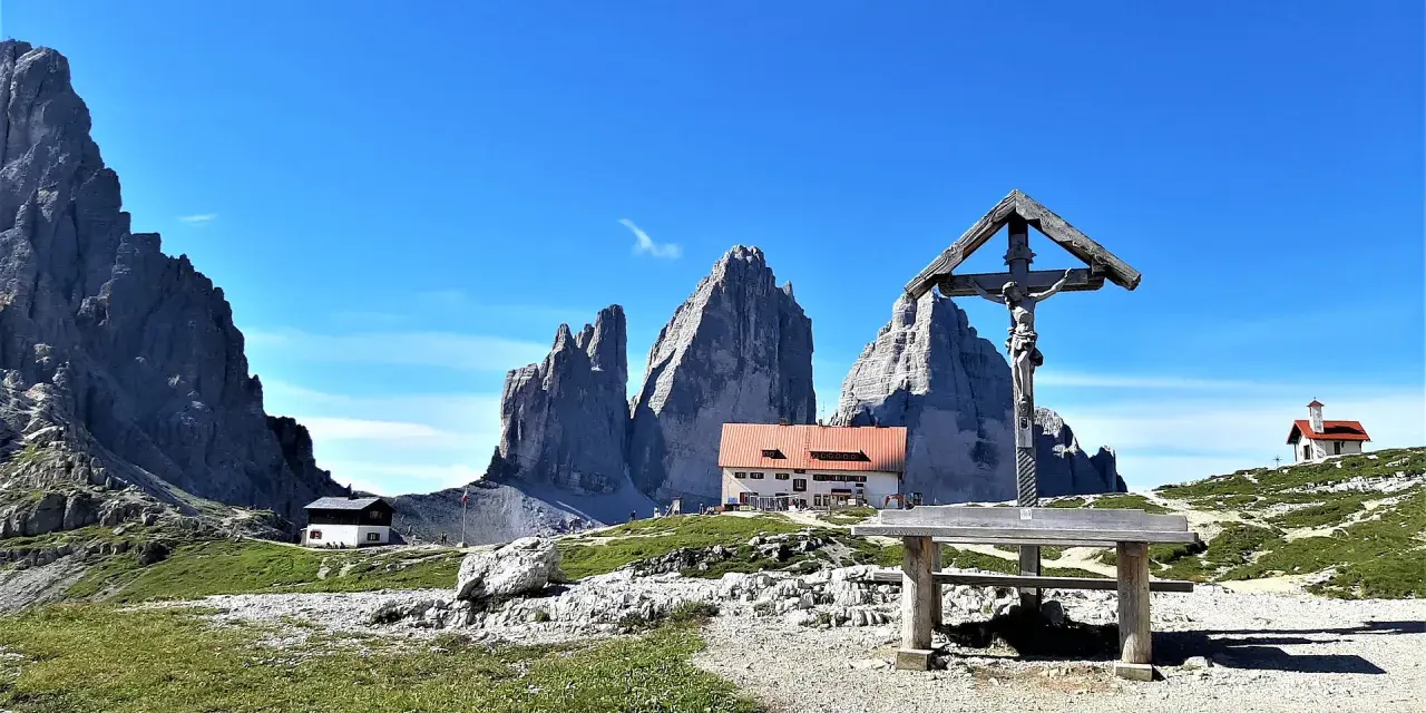 Croce e rifugio al cospetto delle Tre Cime di Lavaredo, un luogo iconico in Val Fiscalina.