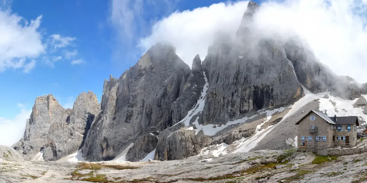 Rifugio Mulaz da Passo Valles, un'oasi di pietra tra le vette dolomitiche avvolte dalle nuvole.