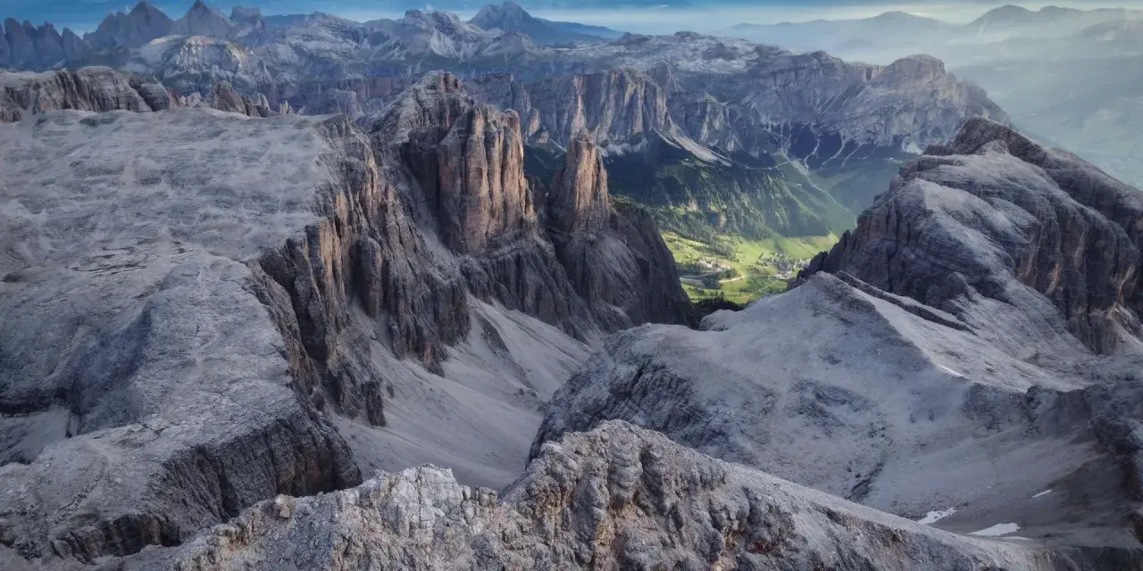 Viste mozzafiato dalle cime rocciose del Piz Boè, con un verde villaggio incastonato tra le valli.