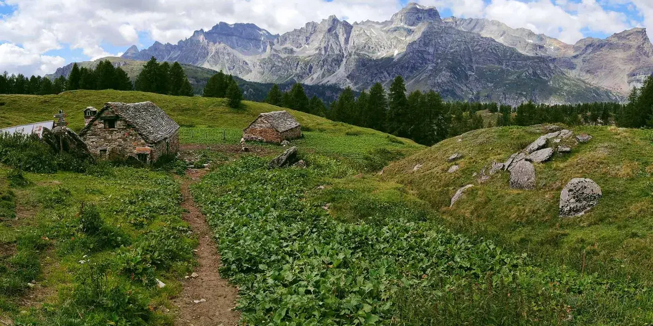 Sentiero per alpe devero trekking tra baite in pietra e montagne maestose.