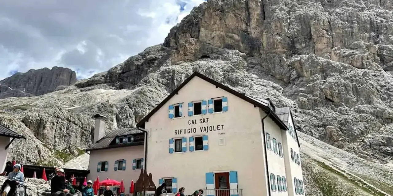 Rifugio Vajolet, punto di partenza per un percorso facile verso le Torri del Vajolet. Persone riposano sotto le imponenti rocce.