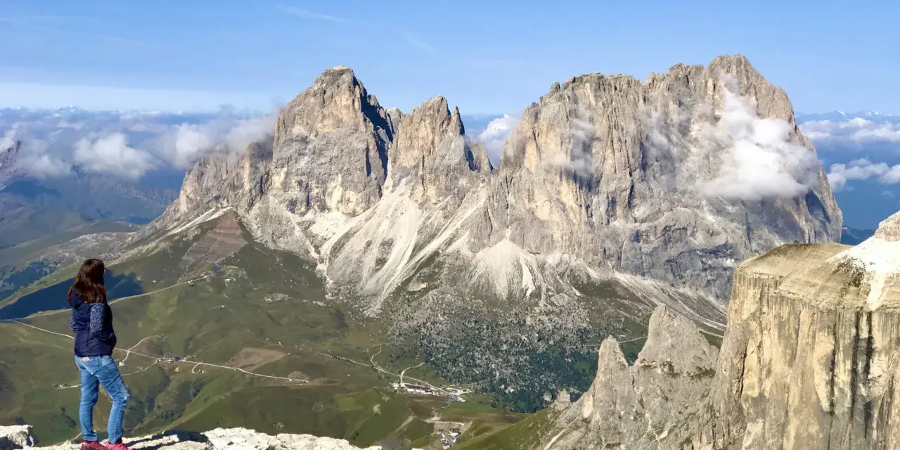 Ragazza ammira la terrazza delle Dolomiti. Per arrivare, prendi la funivia da Canazei.