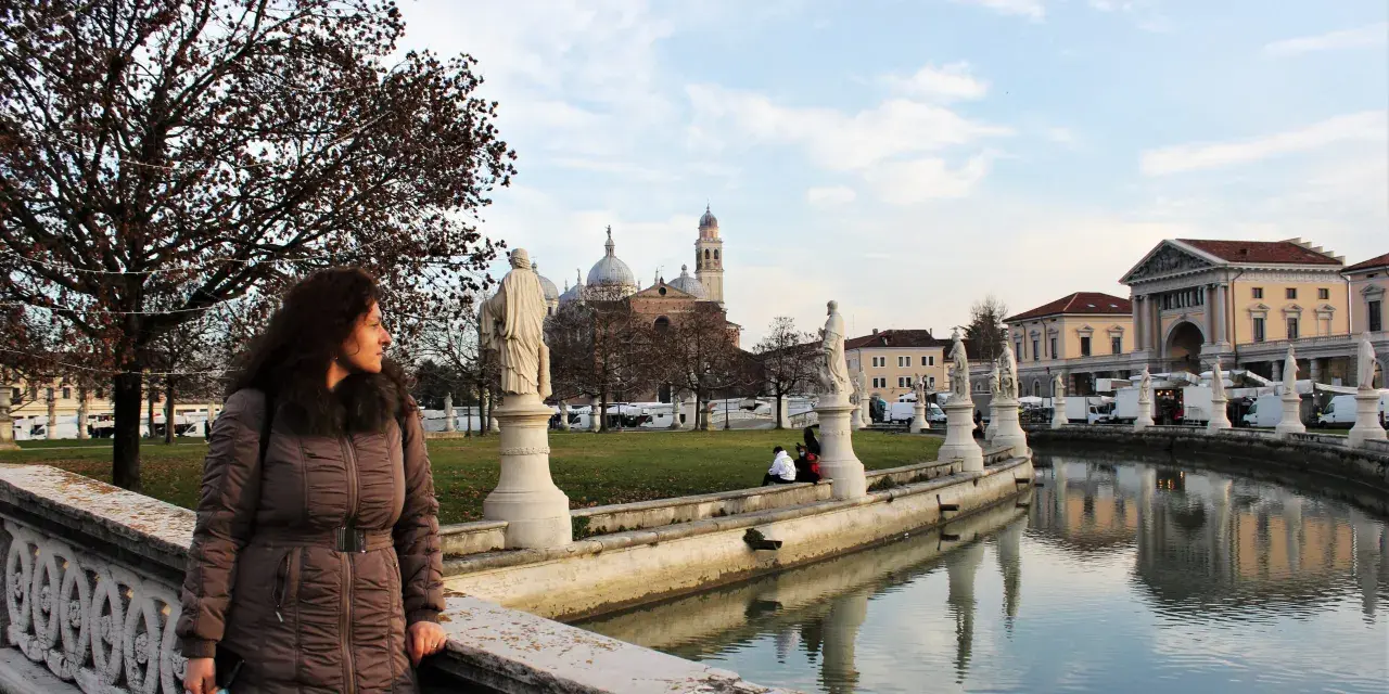 Una donna ammira il panorama di Padova in un giorno d'inverno, con statue, canali e la Basilica di Sant'Antonio sullo sfondo.