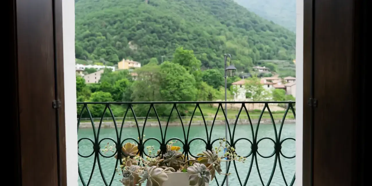 Balcone fiorito con vista sul lago e montagne verdi, un angolo di pace a Cismon del Grappa.