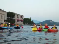Persone in kayak sul lago verde, con un antico edificio sullo sfondo, vicino a San Vigilio di Marebbe.