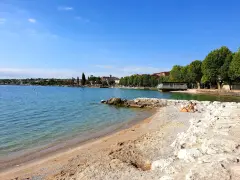 Spiaggia Desenzanino con persone che prendono il sole. Informazioni sui prezzi disponibili online per godersi il lago.