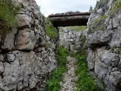 Trincea scavata nella roccia sul Monte Ortigara, con un tetto di tronchi. Per sapere come arrivare, cerca sentieri storici.